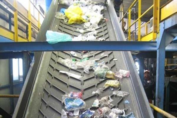 waste being transported on a flighted chevon conveyor belt