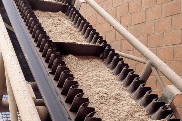 sand being transported in a flighted sidewall conveyor belt